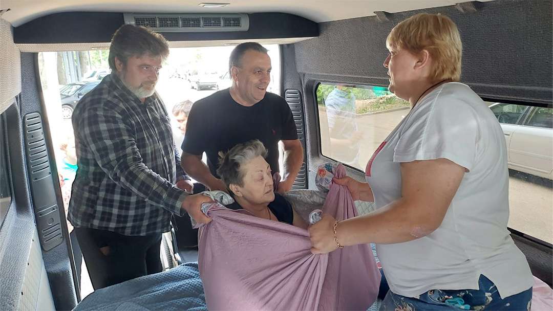 Drivers Sergey and Kolya and daughter Lina help Galyna into the van. | Photo: C4I