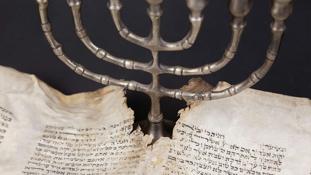 Old scrolls of the Bible and a Menorah. | Photo: Unsplash
